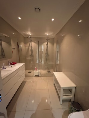 Une salle de bain moderne avec une douche à parois de verre, un meuble-lavabo blanc et un banc.