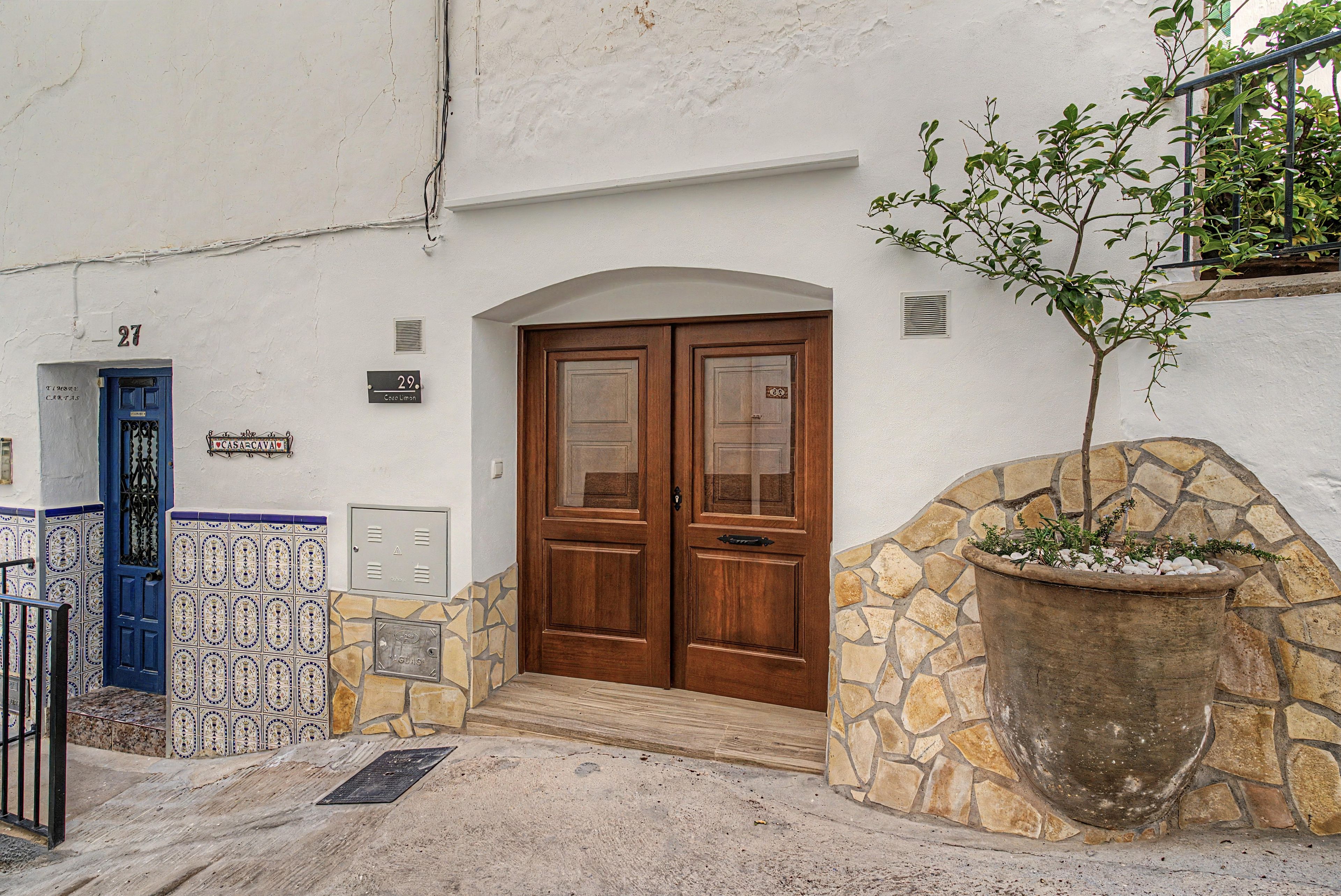 Fachada de edificio con puerta doble de madera, pared de piedra y acceso con baldosas.