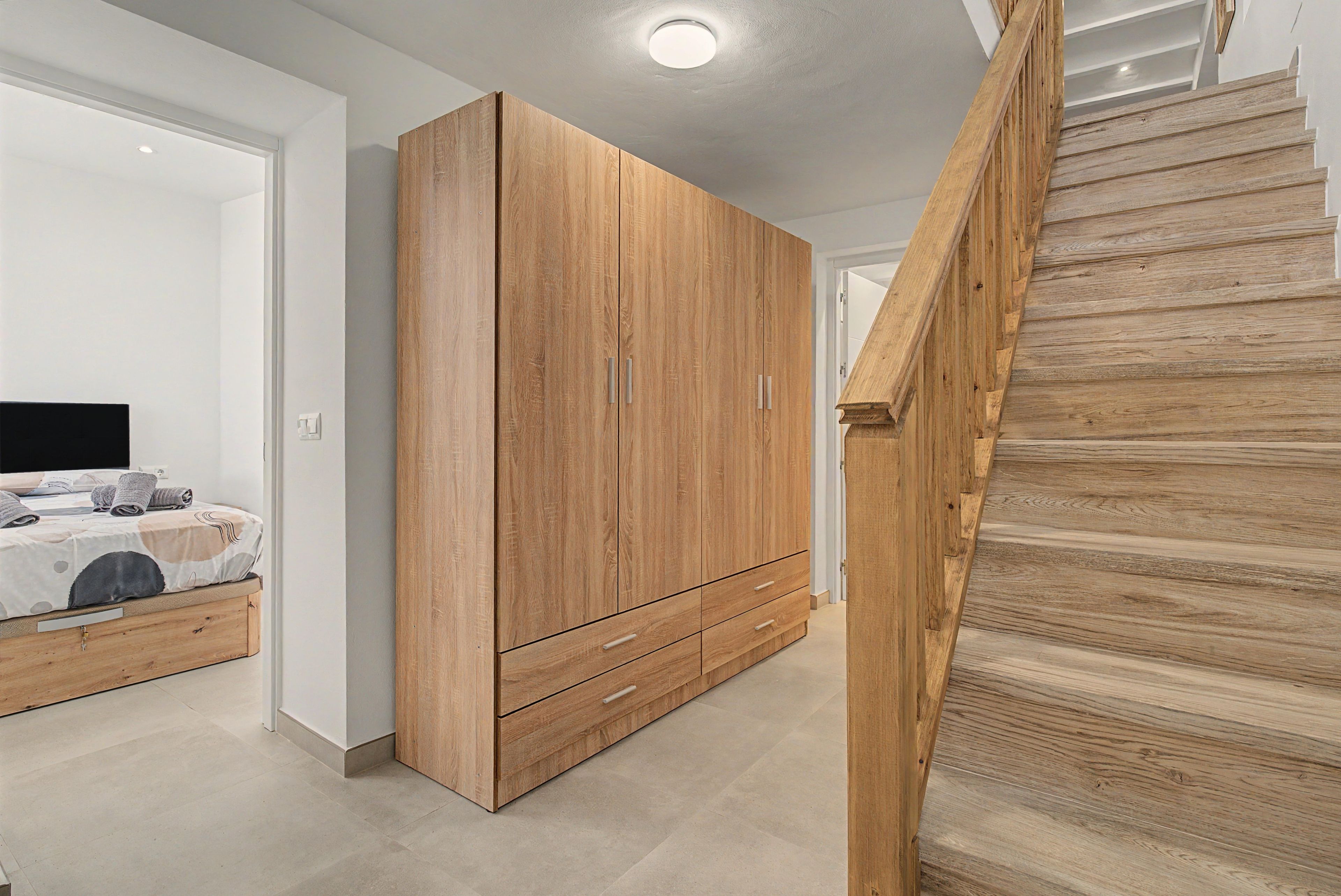 Un dormitorio con una cama, un armario de madera grande y una escalera de madera.