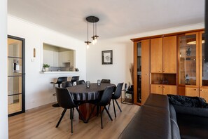 Ein zeitgemäßer Wohnraum mit Essbereich, einem schwarzen Sofa und einer Holzkabine mit Glastüren.