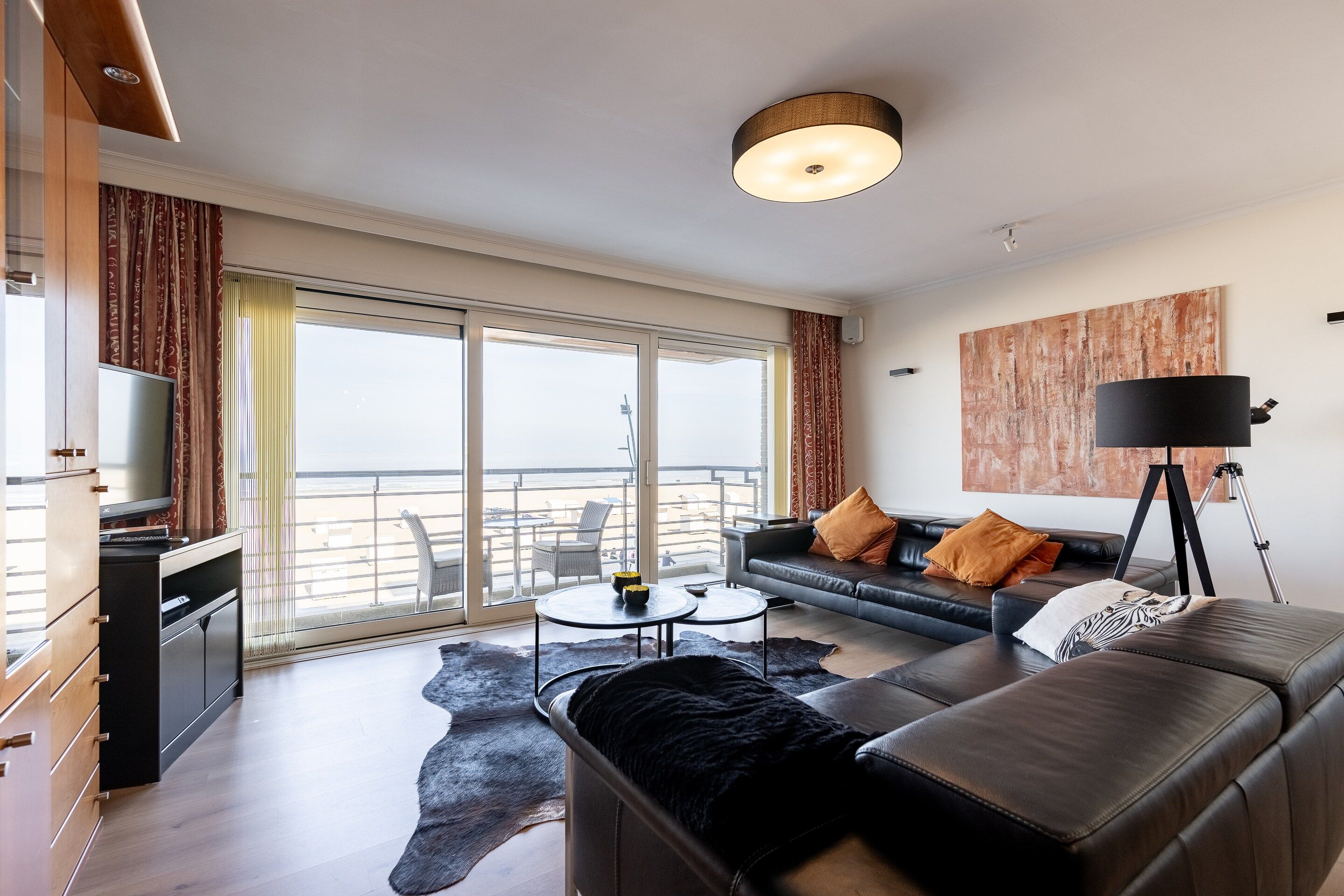 Un salon moderne avec un canapé, une table basse, un téléviseur et un balcon offrant une vue agréable.