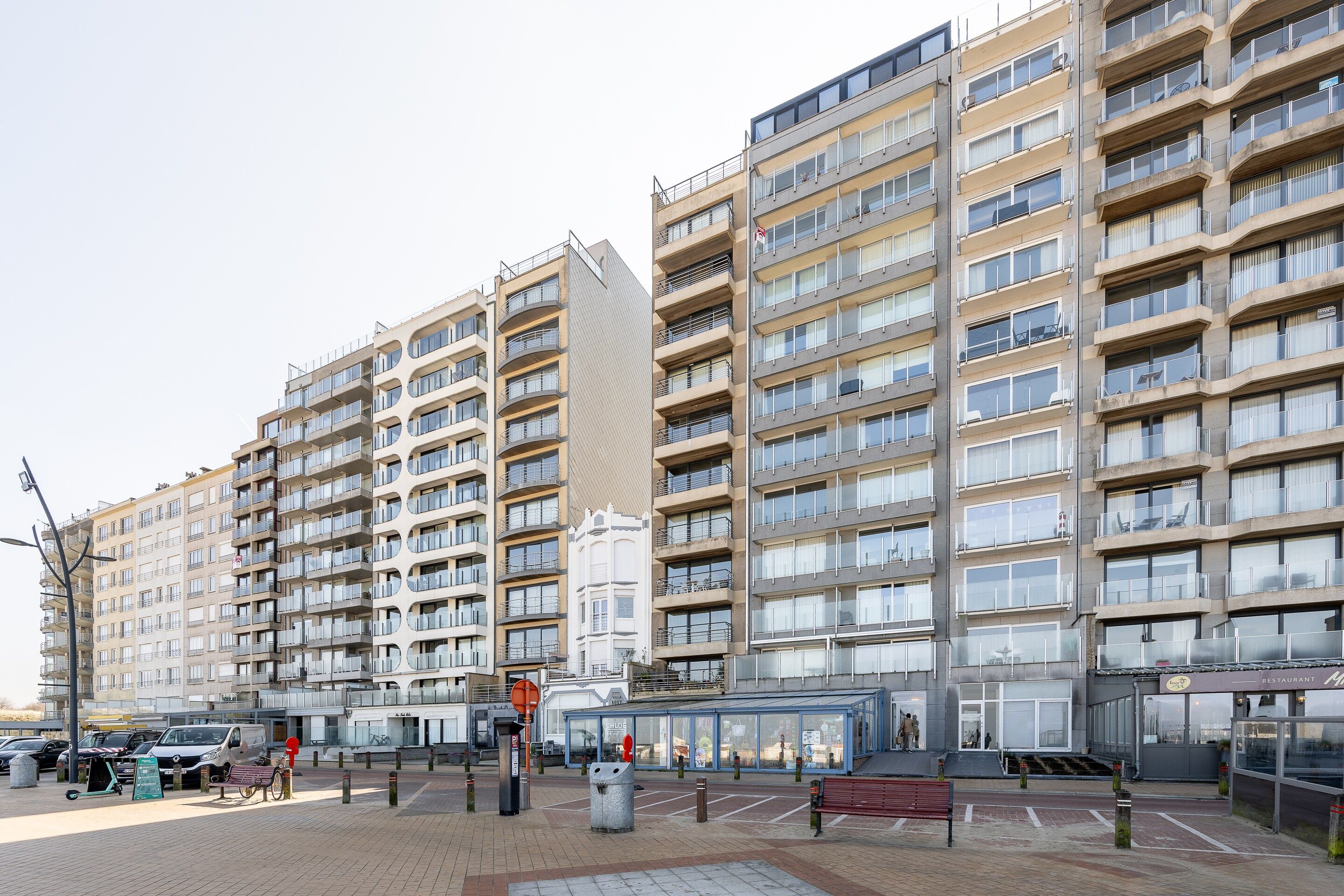 A multi-story residential building with balconies, a pedestrian walkway, and a restaurant.