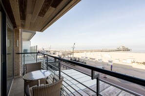 A balcony with wicker furniture and a view of the beach and pier. - Apartment in Zeedijk With Stunning Sea Views (Blankenberge)