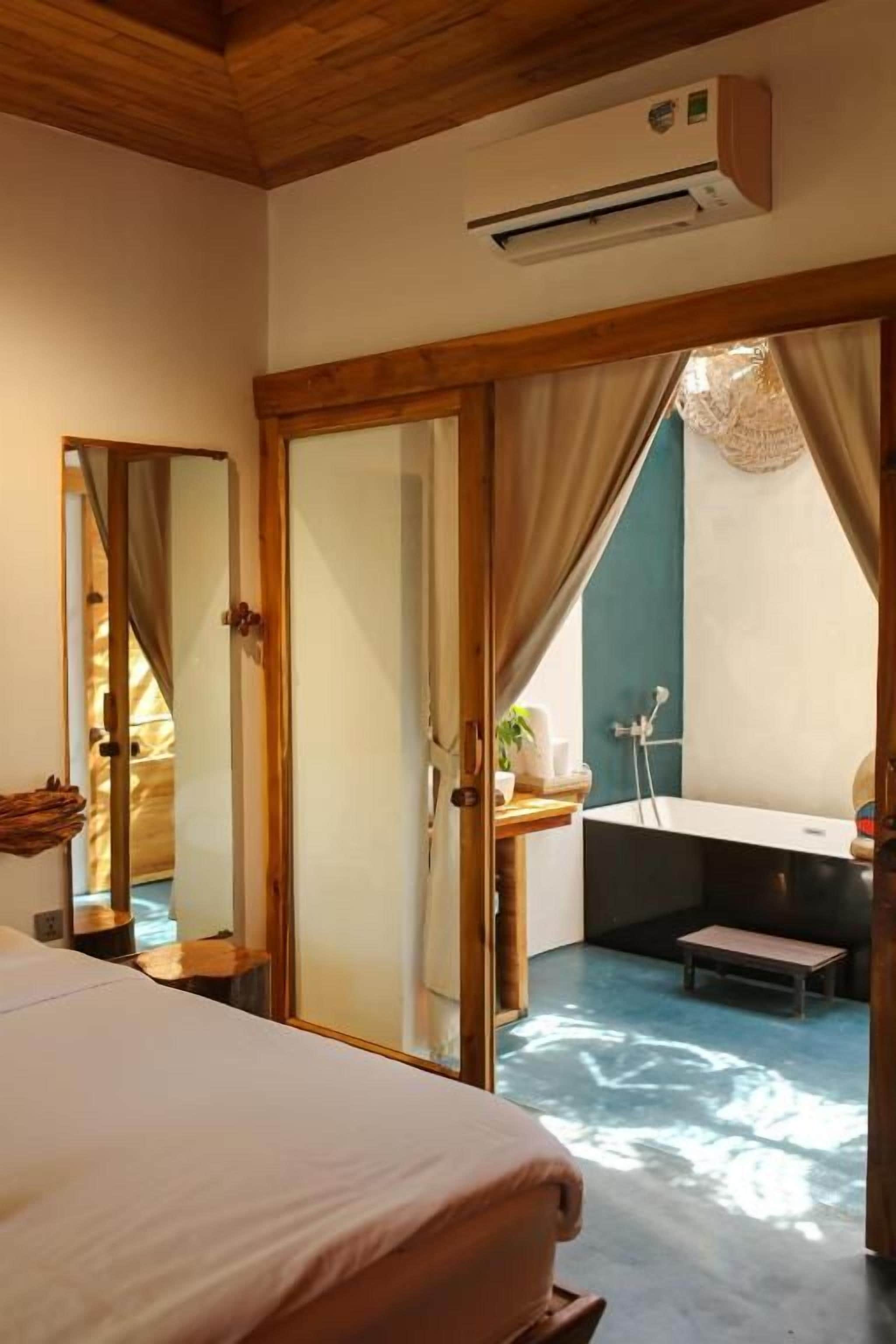 A bedroom with a bed, a bathroom with a bathtub, and a large window.