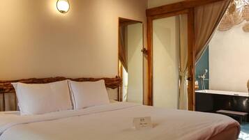 A hotel room with a bed, a bedside table, a mirror, and a window with curtains.