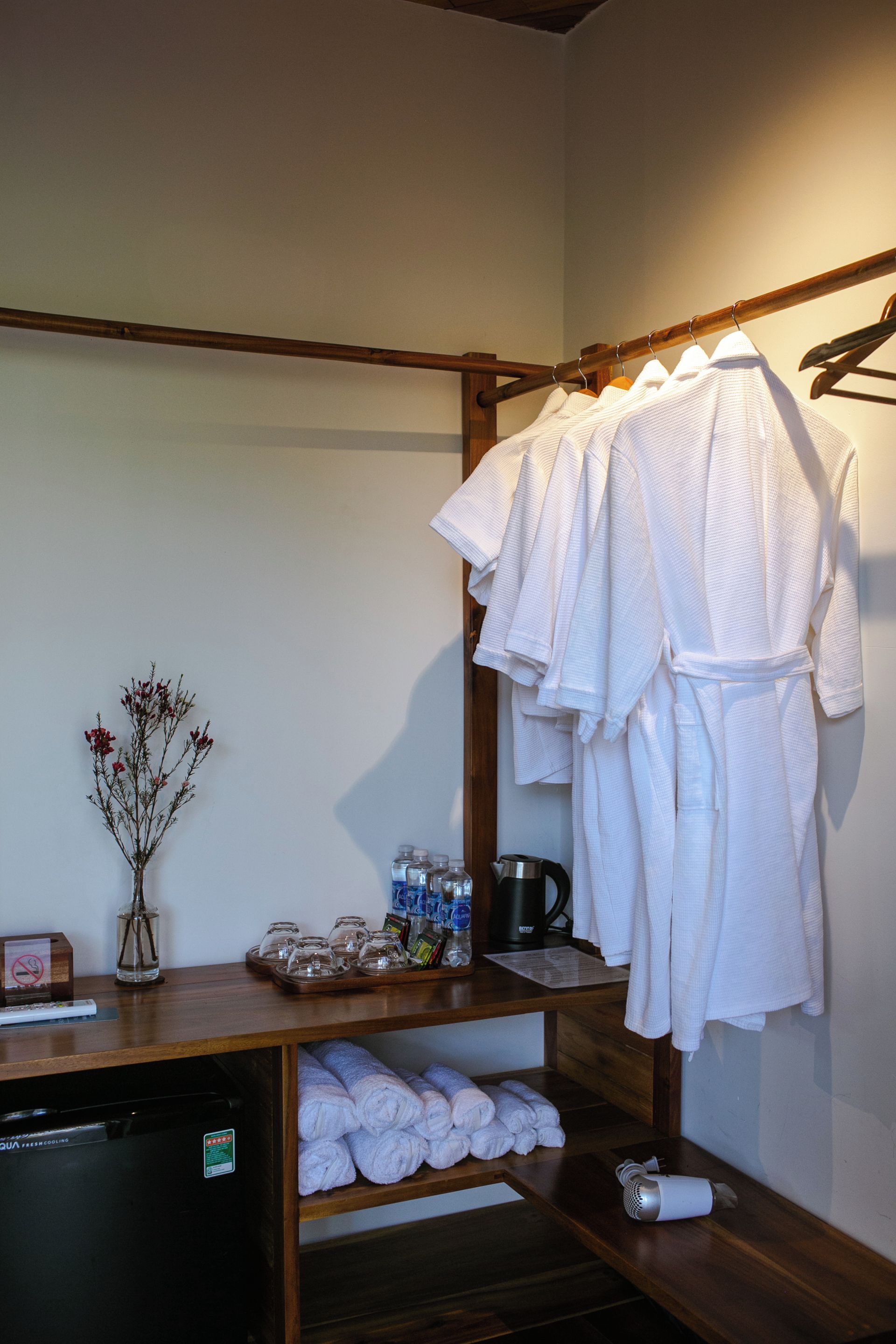 Een badkamer met een houten plank met handdoeken, een haardroger en toiletartikelen.