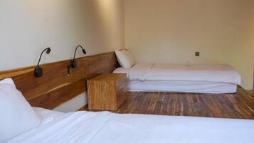 Ein Zimmer mit zwei Betten, einem Holzkopfstück, einem Nachttisch und Wandlampen.