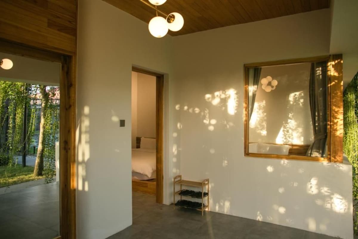 Un interior moderno con techo de madera, un ventanal con vista a árboles y un zapatero.