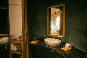 Un baño con lavamanos independiente, un espejo y un perchero para toallas.