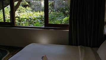 A hotel room with a bed, a window, and a view of a garden.