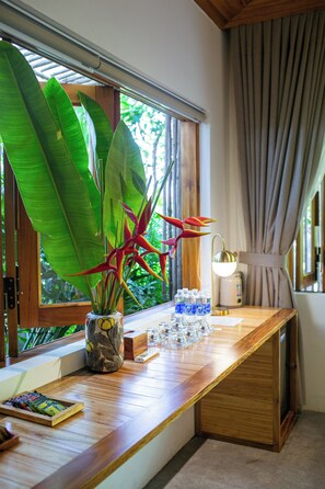 A wooden desk with a potted plant, a water dispenser, and a remote control.