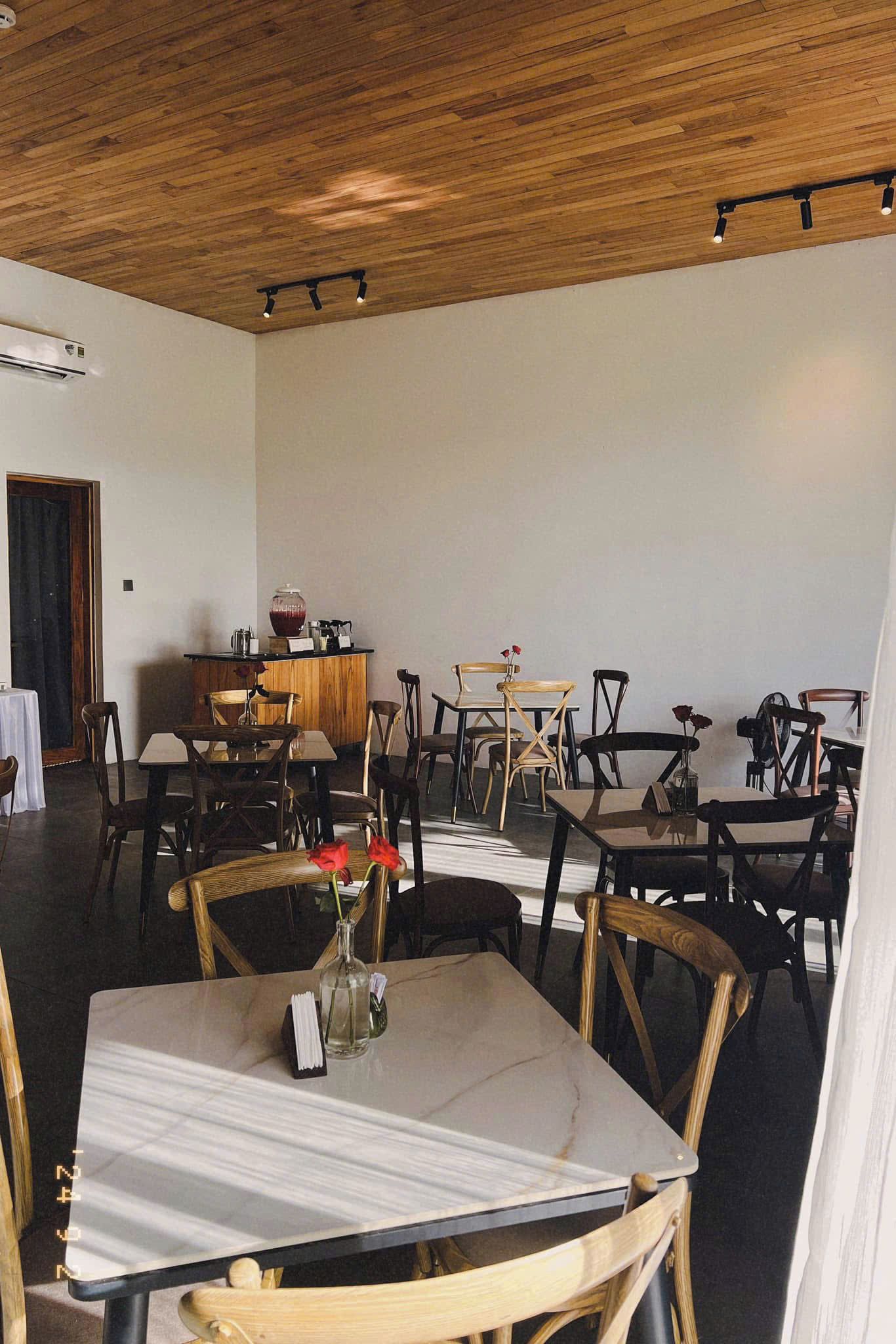 A restaurant interior with wooden ceiling, tables, chairs, and a bar area.