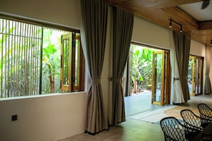 A room with large windows, a ceiling fan, and a view of greenery outside.