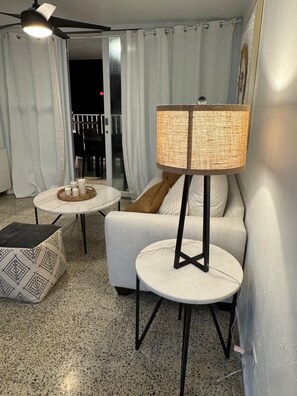 A modern living room with a sofa, two round tables, a floor lamp, and a ceiling fan. - Luxury beachfront apartment (Luquillo)