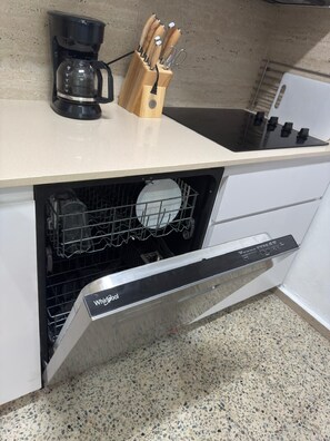 A kitchen with a built-in dishwasher, a coffee maker, and a knife block. - Luxury beachfront apartment (Luquillo)