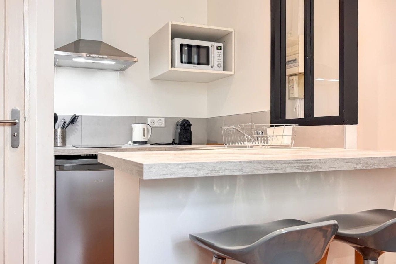 A modern kitchen with a built-in microwave, a coffee maker, and a dish rack.