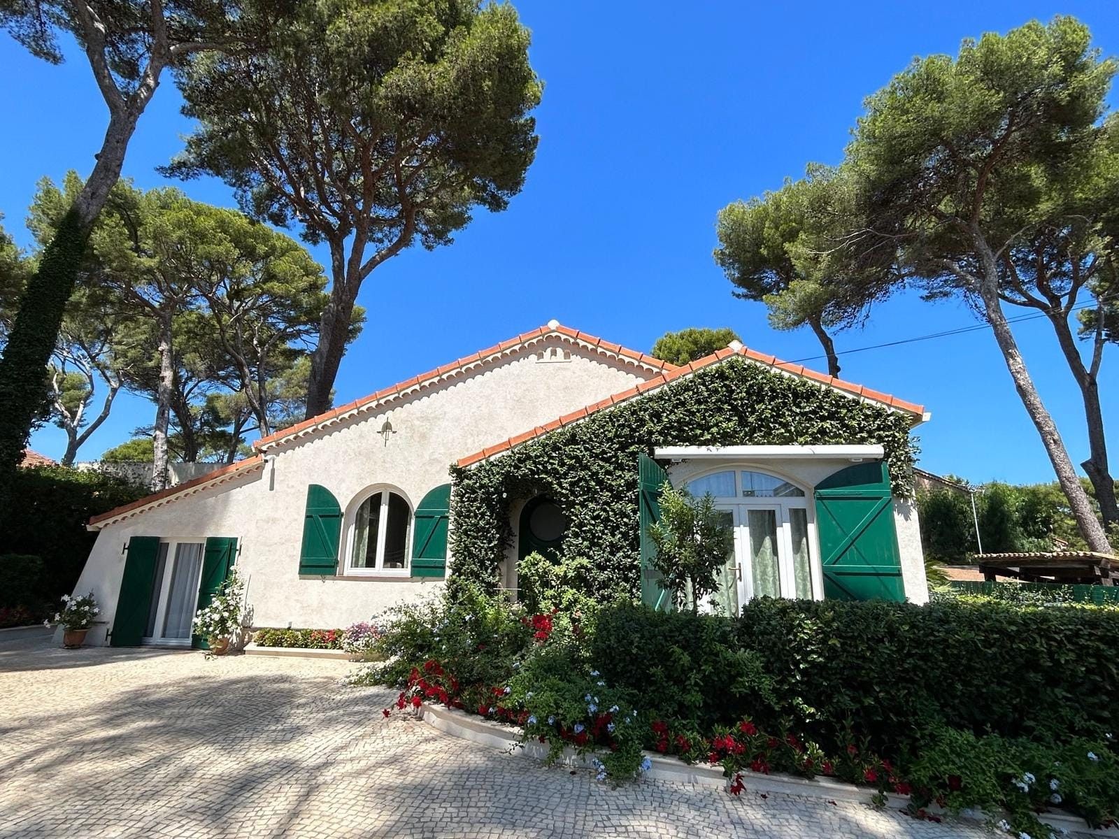 Un edificio con facciata bianca, persiane verdi e tetto a tegole.