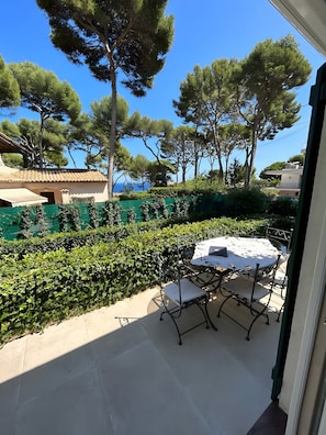 A patio with a table and chairs, surrounded by greenery and trees. - Villa 'Sea View Cap D’Antibes' with Sea View, Wi-Fi and Air Conditioning (Antibes)