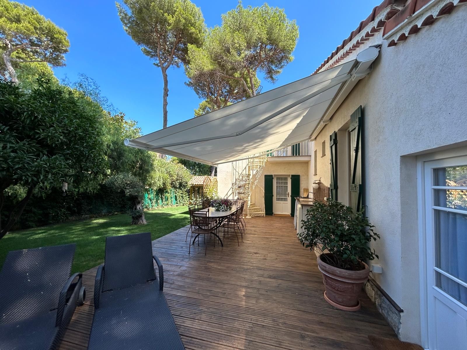 Un patio con tavolo e sedie, una zona coperta e una pianta in vaso.