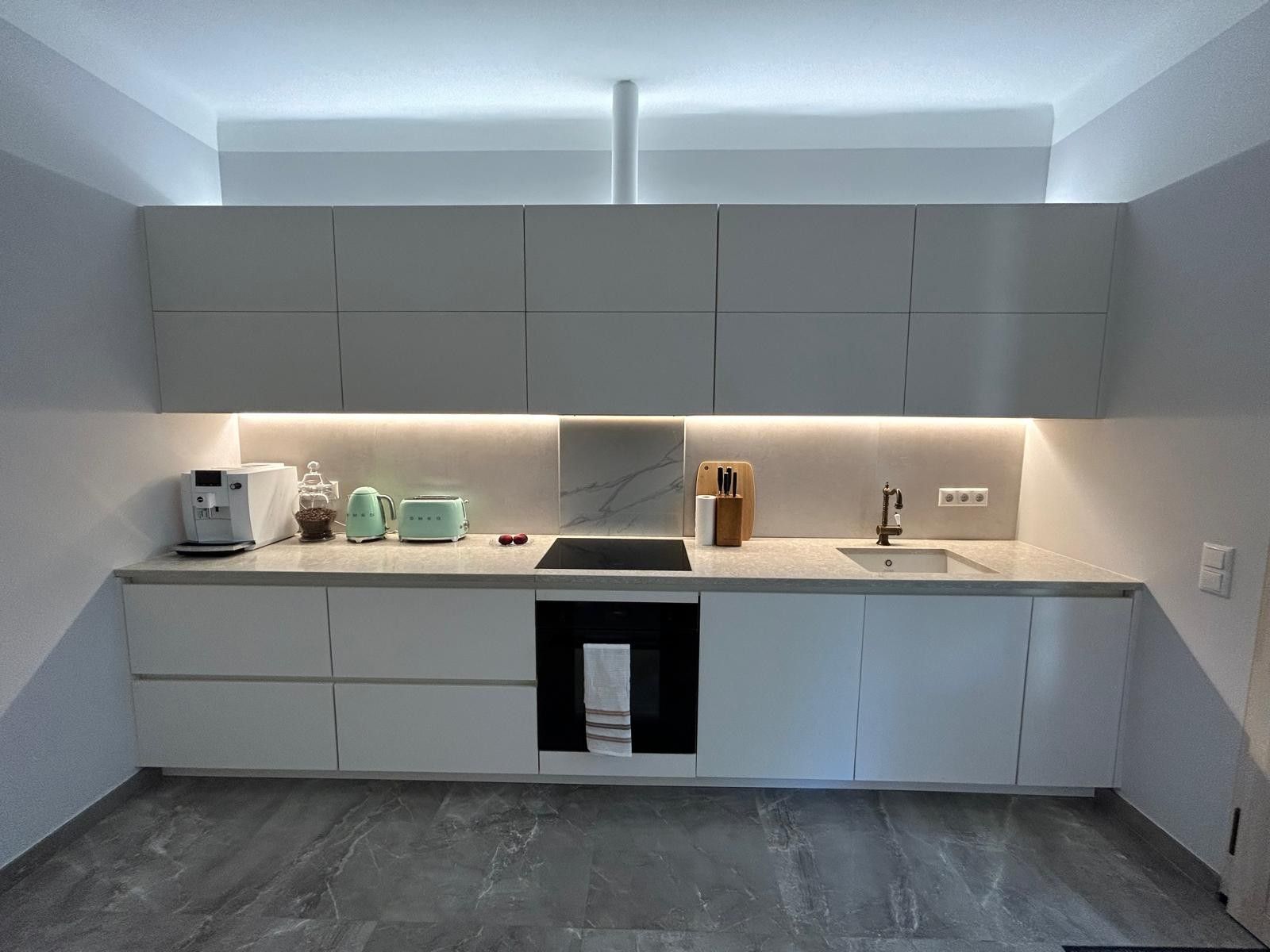A modern kitchen with a built-in dishwasher, a sink, and a countertop with a coffee maker and toaster.