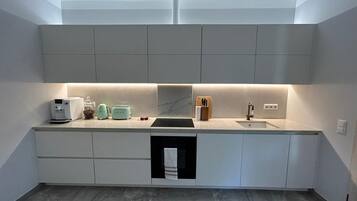 A modern kitchen with a built-in dishwasher, a sink, and a countertop with a coffee maker and toaster.