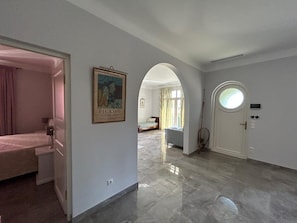 A hotel room with a bed, a door with a circular window, and a framed artwork on the wall. - Villa 'Sea View Cap D’Antibes' with Sea View, Wi-Fi and Air Conditioning (Antibes)