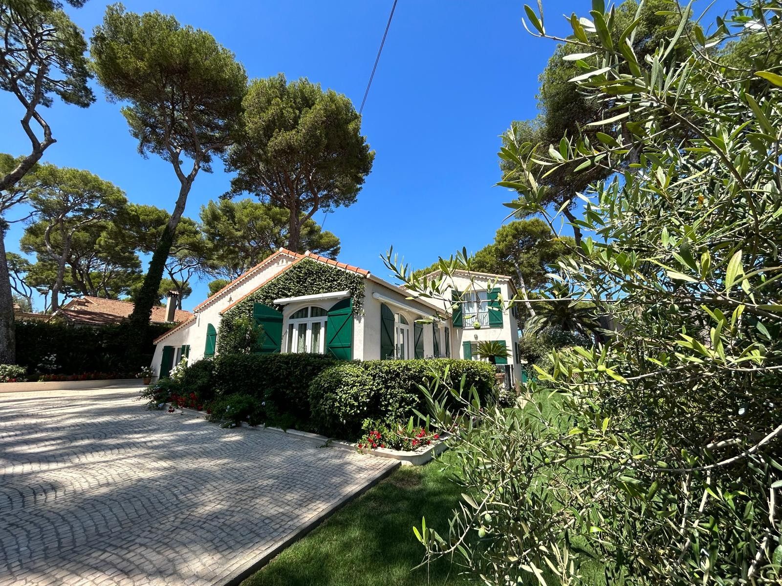Una casa a due piani con tetto in tegole, persiane verdi e vialetto lastricato.