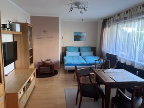 Ein modernes Zimmer mit einem Bett, einem Fernseher, einem Esstisch und einem Bücherregal.