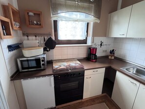 Eine kleine Küche mit Mikrowelle, Kaffeemaschine und Herd.