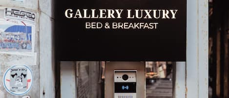 A sign for 'Gallery Luxury Bed & Breakfast' with a keypad and a wooden plaque below it.