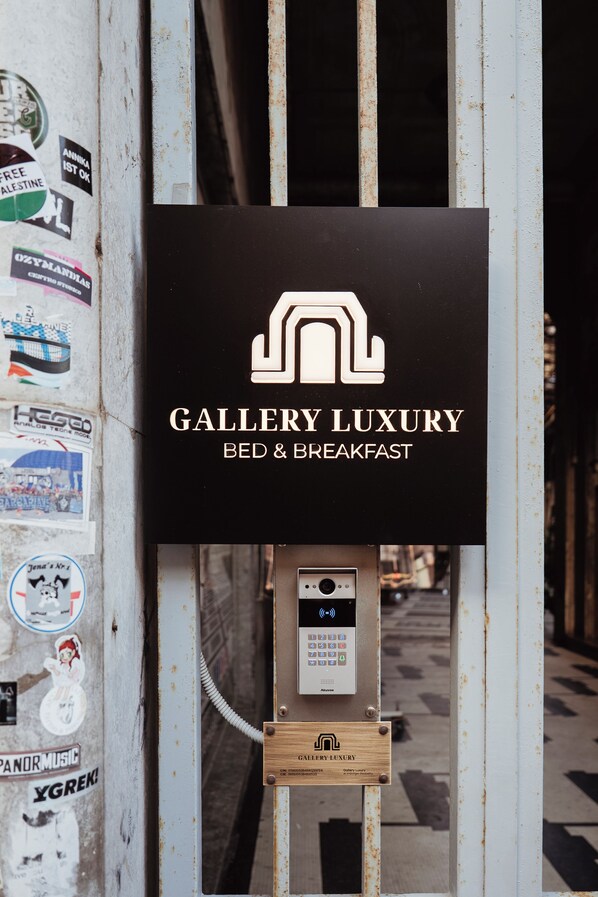 En skylt för ”Gallery Luxury Bed & Breakfast” med en knappsats och en träplatta under.