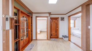 Un couloir avec des portes en bois, un lit et un petit banc.