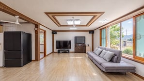 Un salon moderne équipé d’un téléviseur à écran plat, d’un canapé, d’un réfrigérateur et d’un ventilateur de plafond.