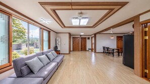 Un vaste espace de vie comprenant un canapé, un plancher en bois et de grandes fenêtres offrant une vue sur l’extérieur.