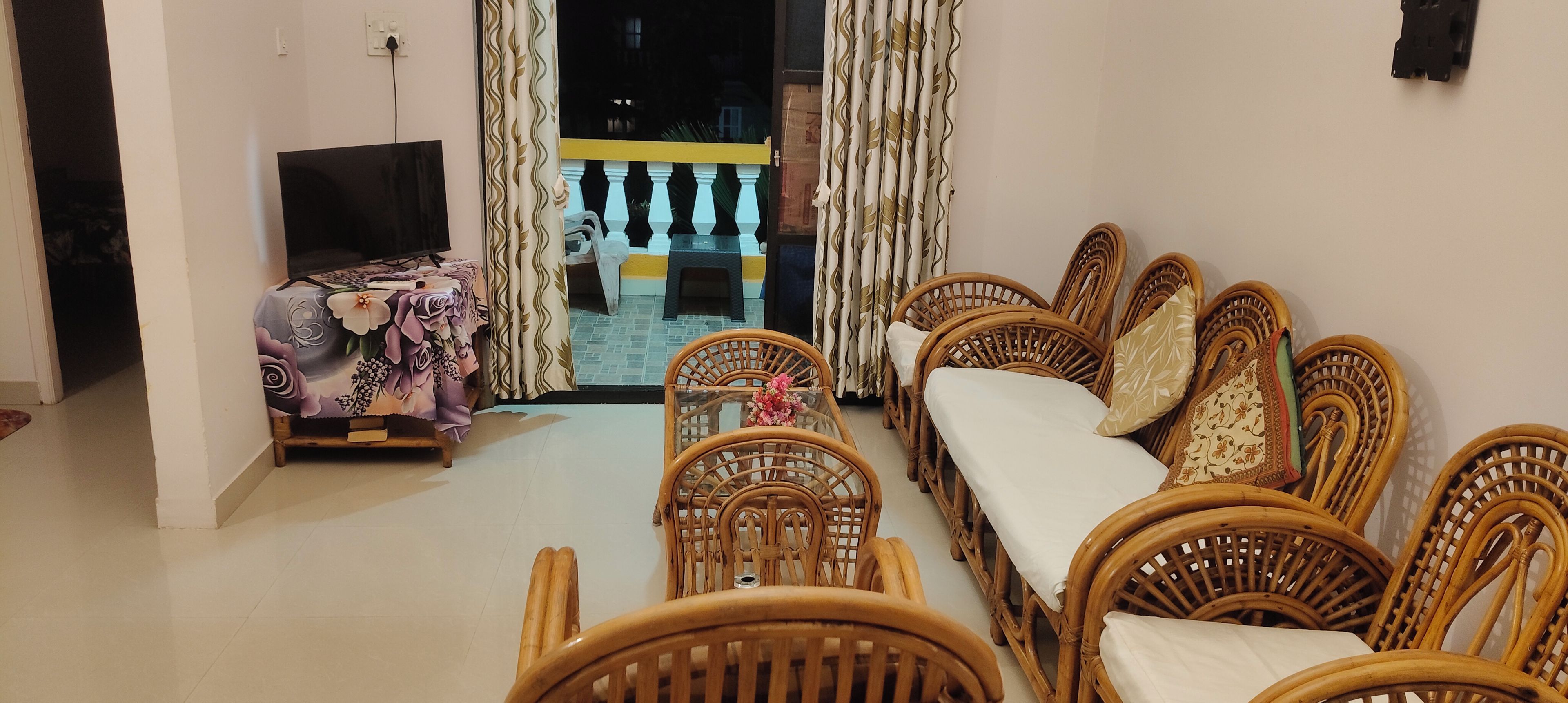 A living room with a sofa set, a television, and a table with a floral tablecloth.