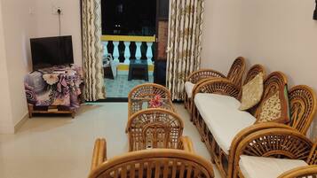 A living room with a sofa set, a television, and a table with a floral tablecloth.