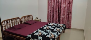 A bedroom with a bed, a nightstand, a potted plant, and a window with curtains. - Reliance sea mist (Morgoa)