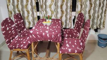 A dining table with a floral tablecloth, surrounded by chairs with a similar pattern.