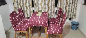 A dining table with a floral tablecloth, surrounded by chairs with a similar pattern. - Reliance sea mist (Morgoa)