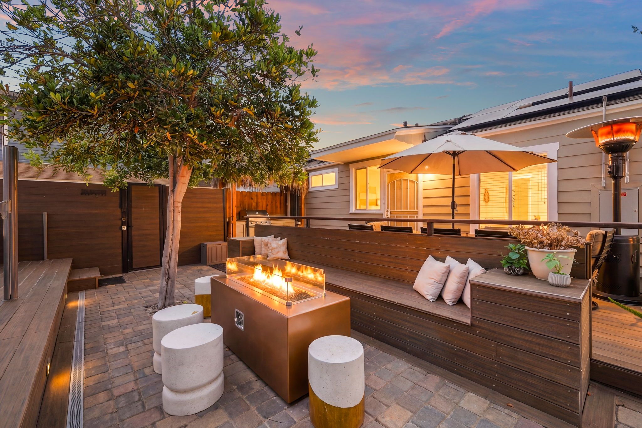 An outdoor patio with a fire feature, seating, and a pergola.