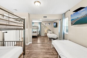 Ett hotellrum med våningssängar, en tv, ett fönster med utsikt över San Diego och en trappa som leder till ett annat rum.