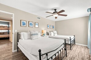 Ein Schlafzimmer mit zwei Betten, einem Deckenventilator und gerahmten Bildern an der Wand.