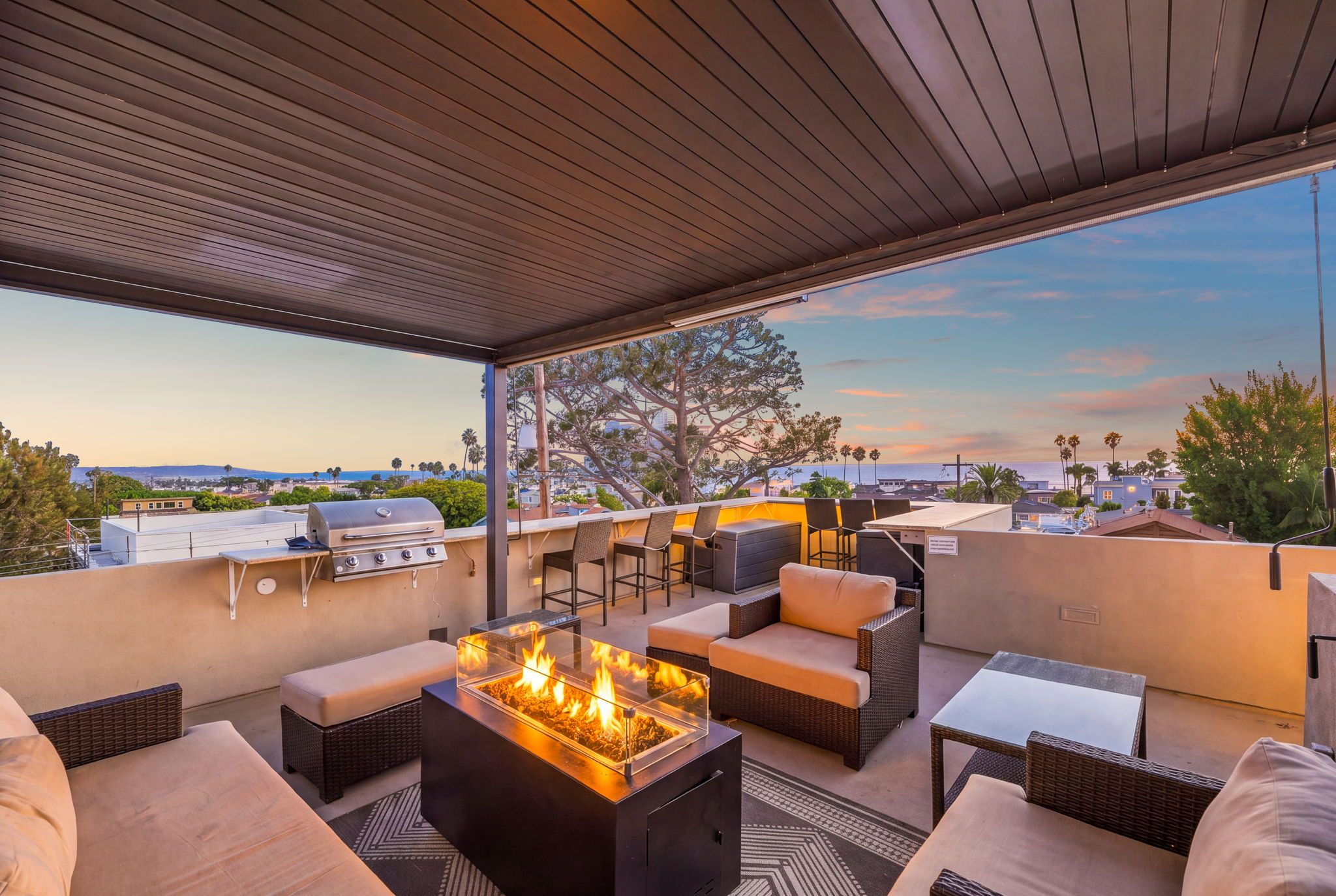 An outdoor patio with a fire feature, seating, and a view of the cityscape.