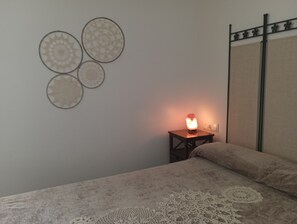 Ein Schlafzimmer mit einem Bett, einem Nachttisch mit Lampe und Wanddekoration.