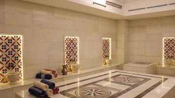 A spa room with a large marble floor, multiple sinks, and decorative tiles.