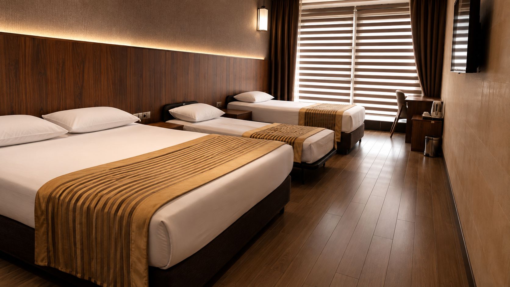 Habitación de hotel con tres camas, un escritorio y un televisor.