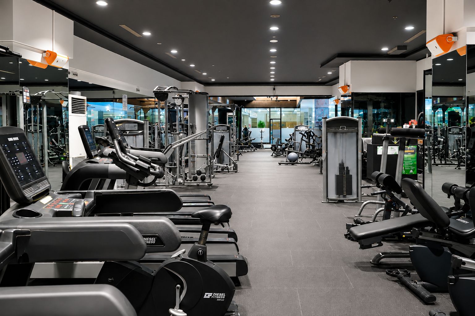 A modern gym with various exercise equipment, including treadmills, weight machines, and free weights.