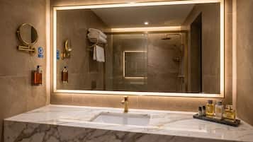A bathroom with a large mirror, a sink, and a shower.