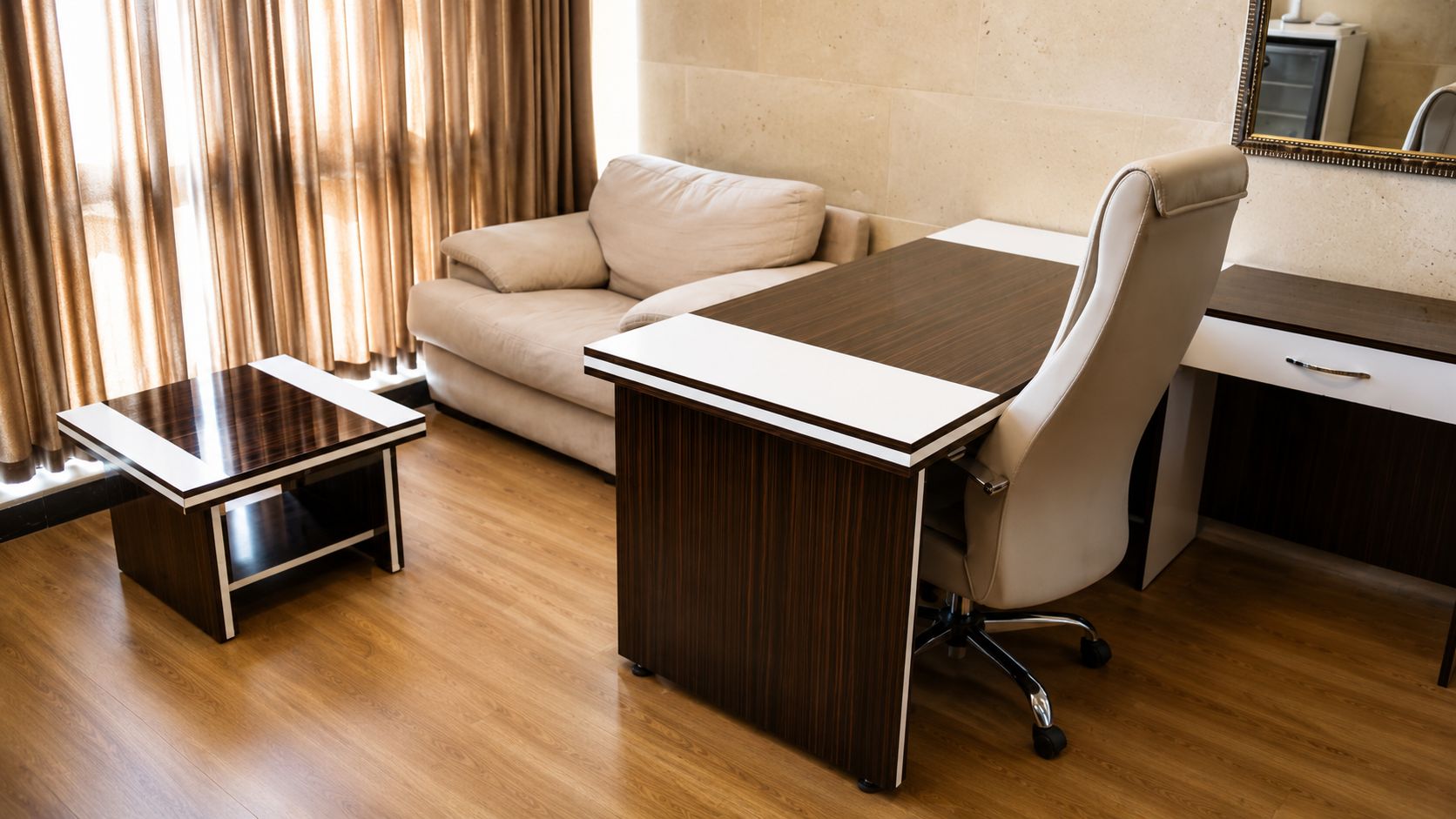 A modern office space with a wooden desk, a white office chair, a small side table, and a beige sofa.