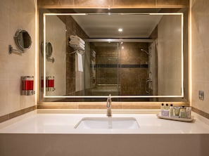 Un baño moderno con un espejo grande, un lavamanos y una ducha.